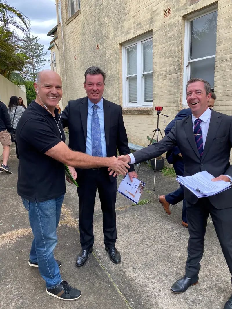 A buyer shaking hands with the agent after winning at auction