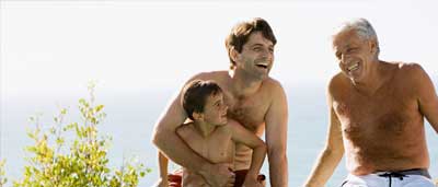 A family's three generations of men, relaxing at the edge of their swimming pool. Laughing together.